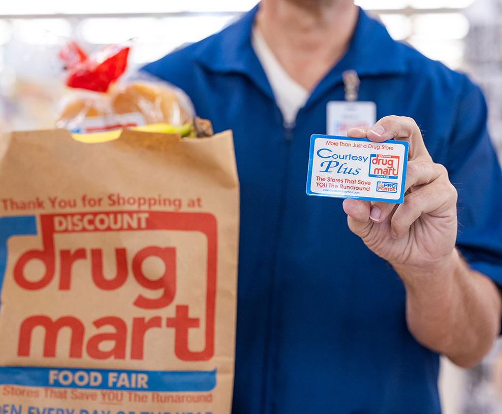 man holding a discount drug mart bag and courtesy plus card